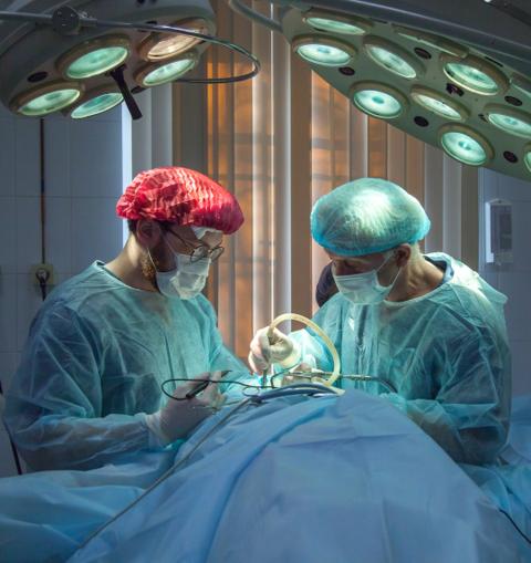 Two doctors are doing surgery for a patient