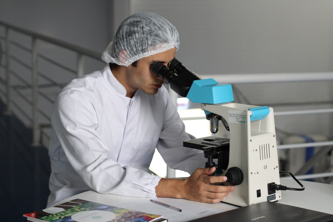 A medical lab technician diagnosing sample with a microscope
