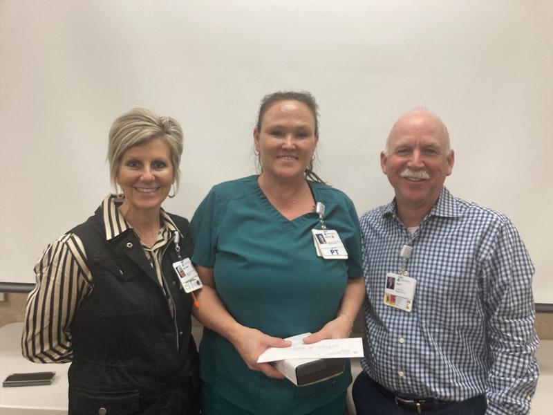 Melanie Flinn, vice president for operations (left), and Interim CEO Jim Parobek (right) recognized Keri W., director of rehab services (center), as White Rock’s Leader of the Month for March.